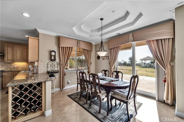 tiled dining room featuring a raised ceiling, crown molding, and sink