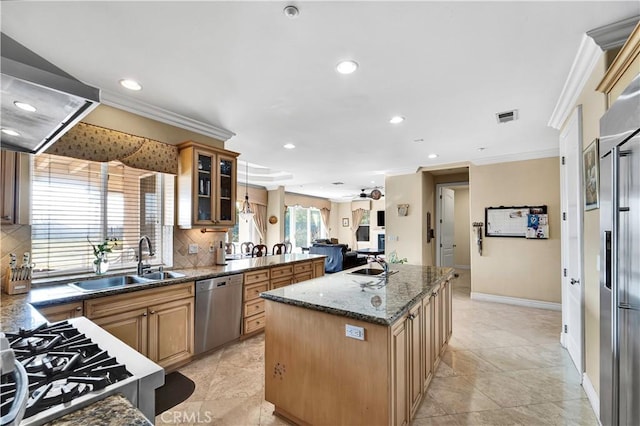 kitchen with sink, ornamental molding, appliances with stainless steel finishes, a kitchen island, and decorative backsplash