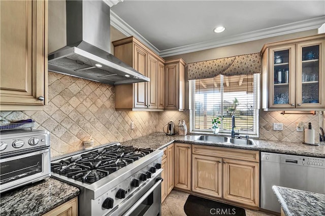 kitchen featuring sink, dark stone countertops, ornamental molding, stainless steel appliances, and wall chimney range hood