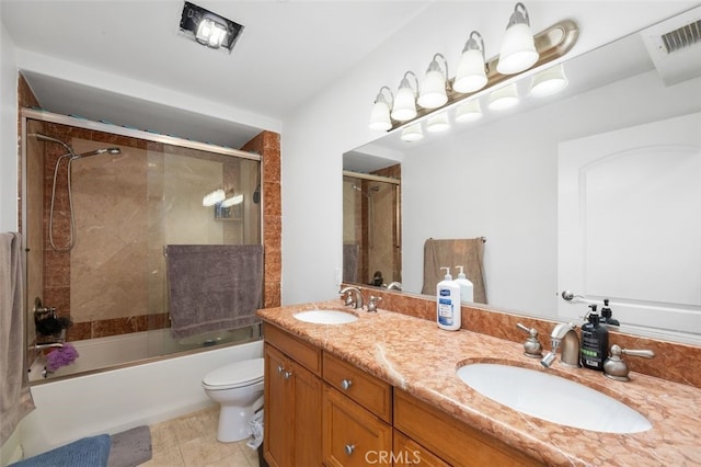 full bathroom featuring vanity, bath / shower combo with glass door, and toilet