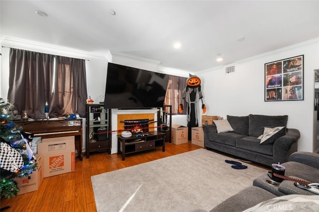 living room with crown molding, a fireplace, and light hardwood / wood-style floors