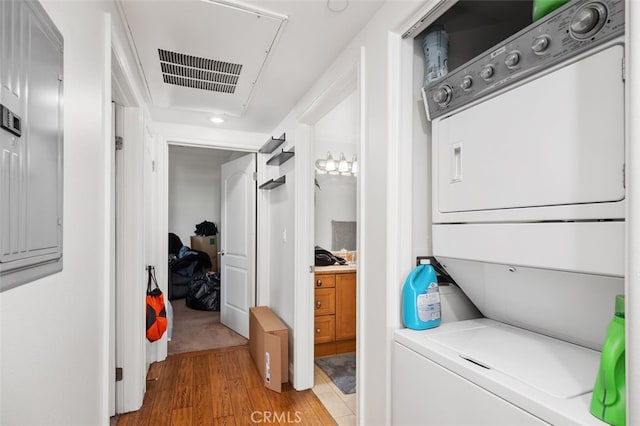 laundry room featuring stacked washer and dryer and light hardwood / wood-style floors