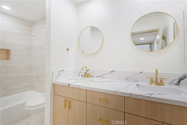 full bathroom featuring vanity, tiled shower / bath, and toilet