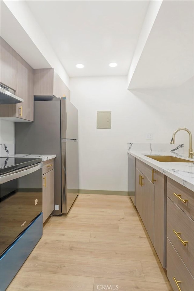 kitchen featuring light stone counters, sink, stainless steel appliances, and light hardwood / wood-style floors