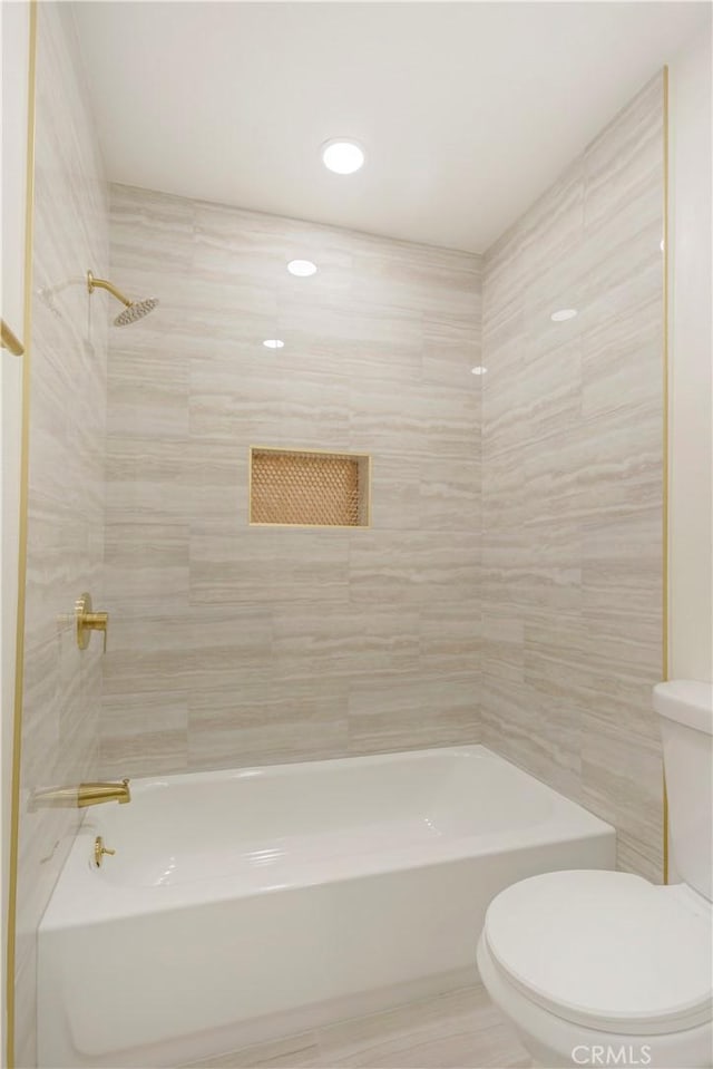 bathroom featuring tiled shower / bath combo and toilet