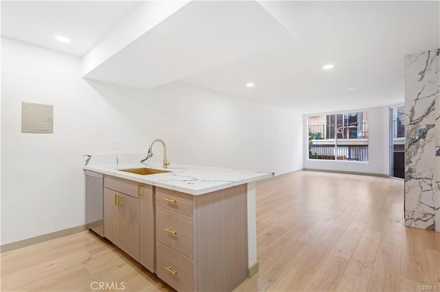 kitchen featuring sink, electric panel, light stone counters, light hardwood / wood-style floors, and kitchen peninsula