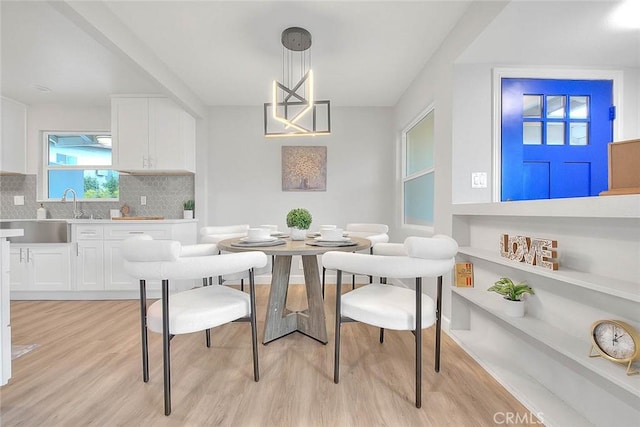 dining room with an inviting chandelier, sink, and light hardwood / wood-style floors