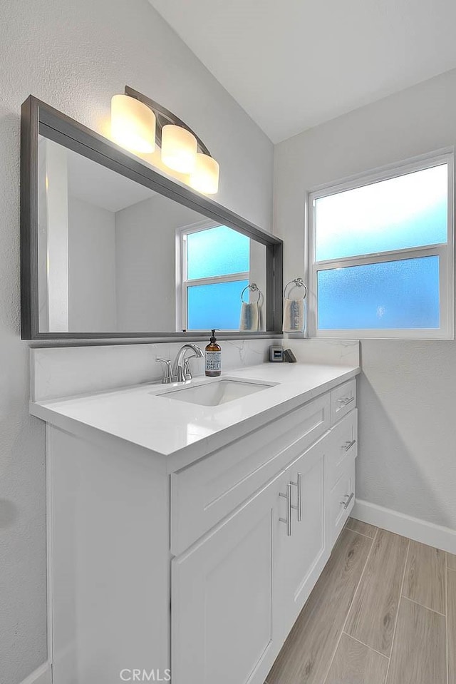 bathroom with hardwood / wood-style flooring, a healthy amount of sunlight, and vanity