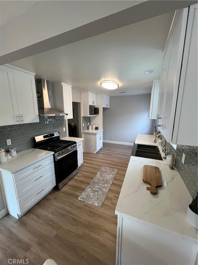 kitchen with white cabinetry, sink, gas stove, dark wood-type flooring, and wall chimney exhaust hood