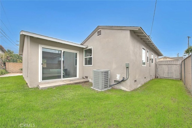 rear view of property featuring central AC and a lawn