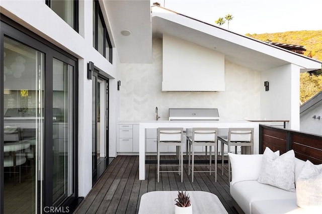 wooden terrace with an outdoor living space and grilling area