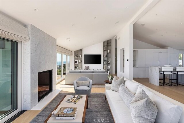 living room with lofted ceiling, a fireplace, and light hardwood / wood-style floors