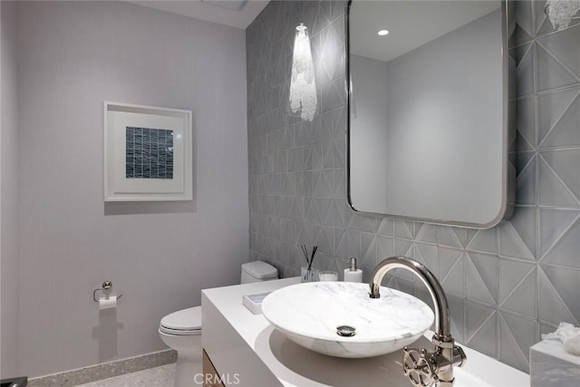 bathroom featuring vanity, tile walls, and toilet