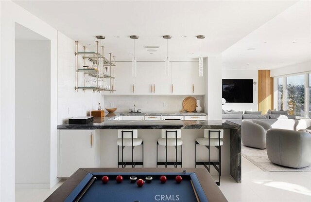 bar with white cabinetry, sink, backsplash, and decorative light fixtures