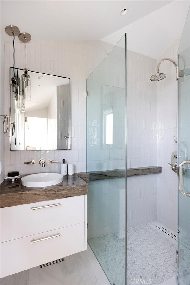 bathroom featuring tasteful backsplash, vanity, a shower with door, and tile walls