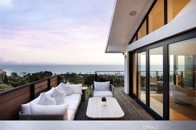 balcony at dusk with outdoor lounge area and a water view