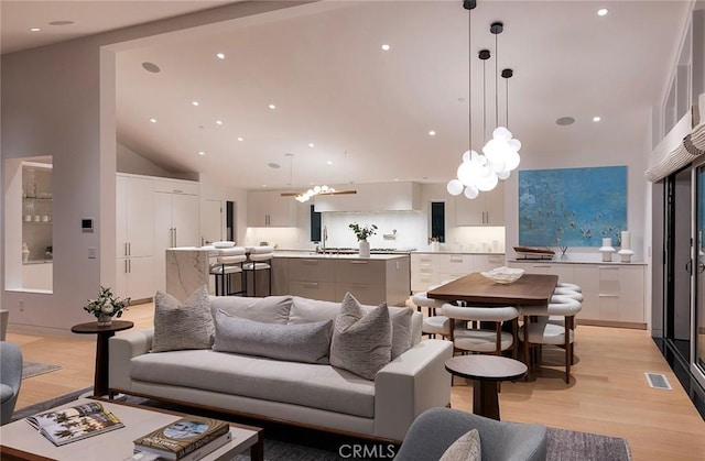 living room with lofted ceiling, sink, and light hardwood / wood-style floors