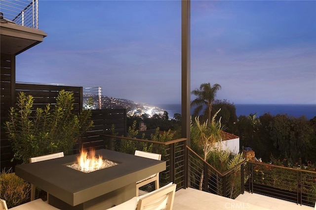 patio terrace at dusk featuring a fire pit and a water view