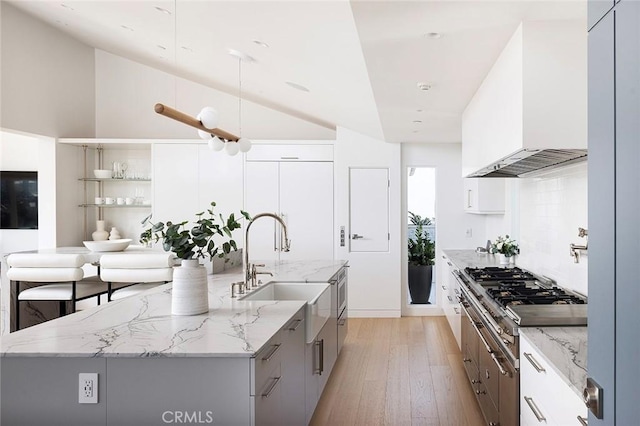 kitchen with custom exhaust hood, white cabinetry, a large island, and sink