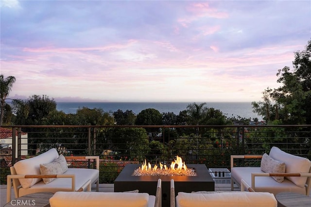 patio terrace at dusk with a water view and an outdoor living space with a fire pit