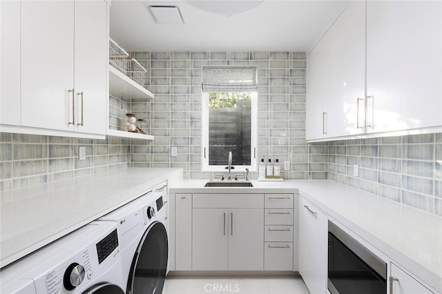 laundry area featuring separate washer and dryer, sink, and cabinets