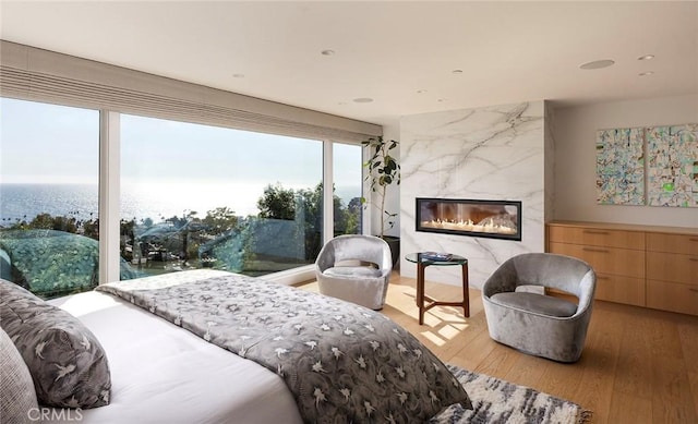 bedroom with a water view, a high end fireplace, and hardwood / wood-style floors