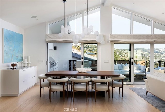 dining area featuring a mountain view, high vaulted ceiling, beamed ceiling, and light wood-type flooring