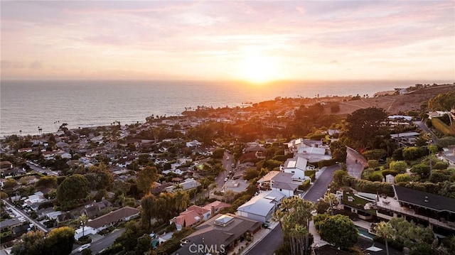 aerial view at dusk featuring a water view