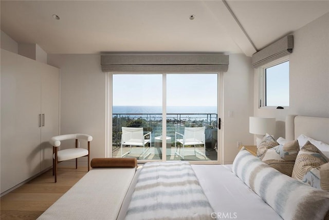 bedroom with hardwood / wood-style flooring, a water view, multiple windows, and access to outside