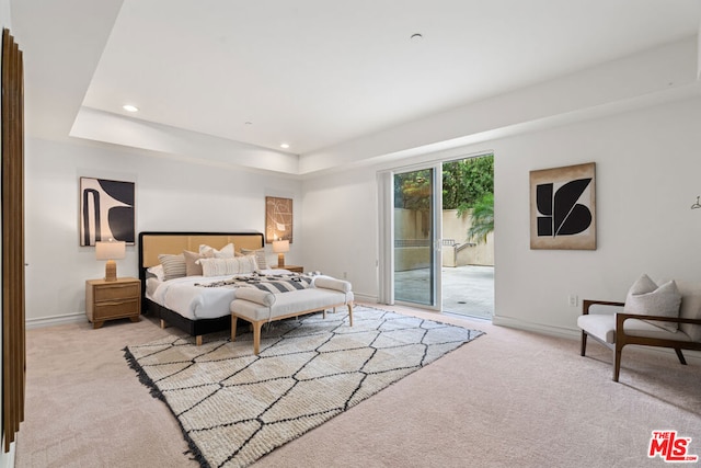 carpeted bedroom with a raised ceiling and access to outside