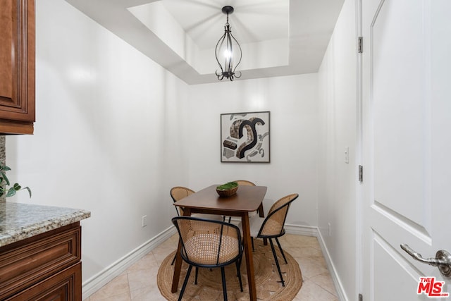 dining room with a raised ceiling, light tile patterned floors, and a notable chandelier