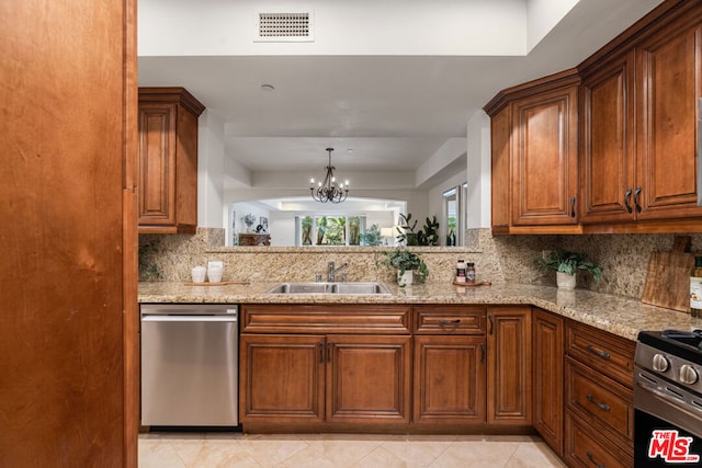 kitchen with sink, a chandelier, decorative backsplash, stainless steel appliances, and light stone countertops