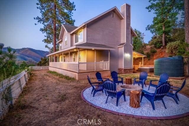 rear view of property with a jacuzzi, a mountain view, and a fire pit