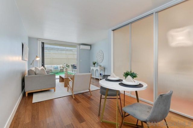 living room with a wall mounted air conditioner and hardwood / wood-style flooring