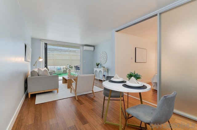 living room featuring hardwood / wood-style flooring, an AC wall unit, and expansive windows