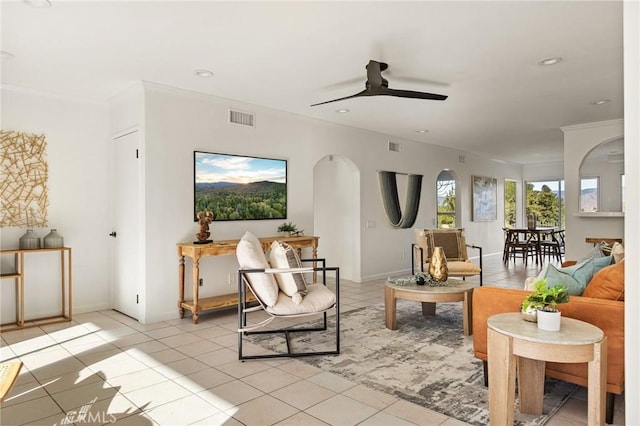 living area with light tile patterned flooring, ornamental molding, and ceiling fan