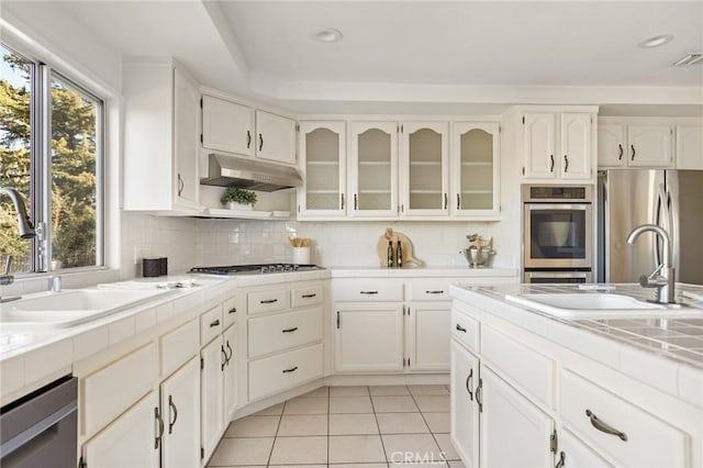 kitchen with stainless steel appliances, light tile patterned flooring, sink, and decorative backsplash