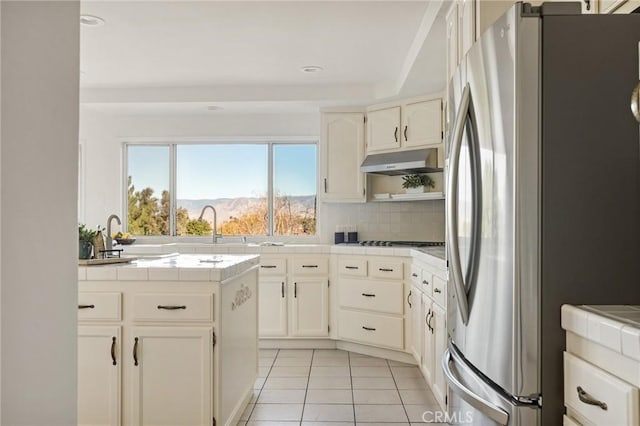 kitchen featuring tile counters, a mountain view, stainless steel fridge, and sink