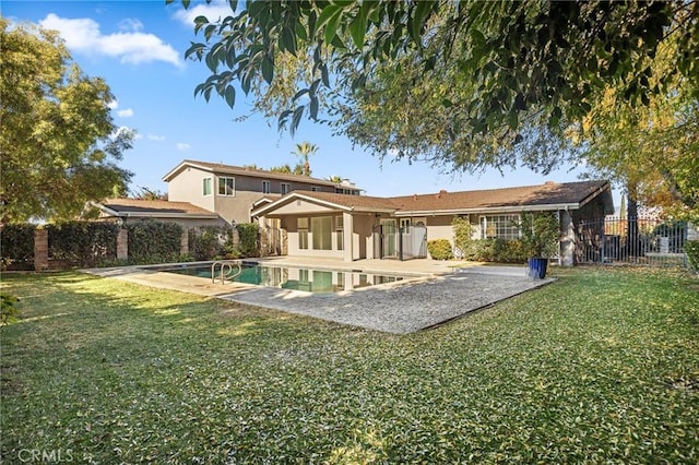 rear view of property with a fenced in pool, a yard, and a patio area