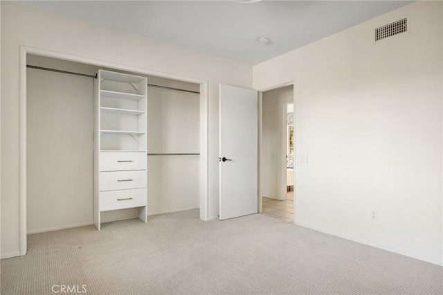 unfurnished bedroom with a closet and light carpet