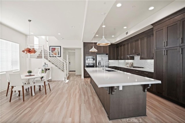 kitchen featuring a large island, sink, hanging light fixtures, stainless steel appliances, and a kitchen bar