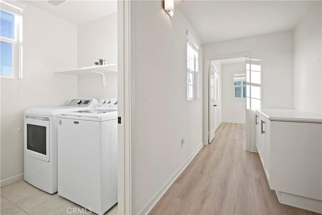 clothes washing area with washer and clothes dryer and light hardwood / wood-style floors