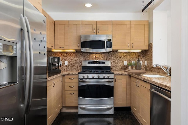 kitchen featuring light stone counters, stainless steel appliances, light brown cabinetry, and sink