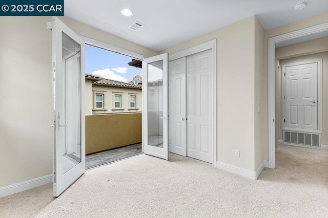 unfurnished bedroom with a closet, carpet floors, and french doors