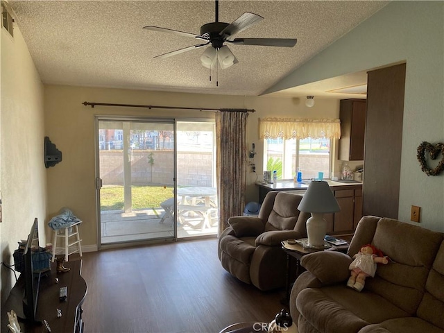 living room with vaulted ceiling, dark wood-type flooring, ceiling fan, and a textured ceiling