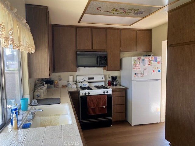 kitchen with white appliances, sink, and light hardwood / wood-style flooring