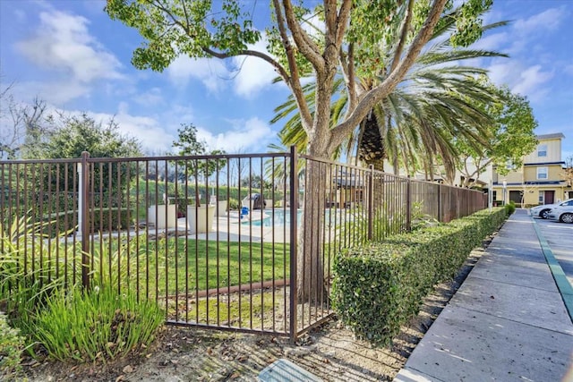 view of gate with a community pool and a lawn