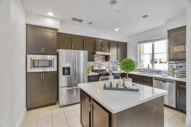 kitchen featuring a kitchen island, sink, decorative backsplash, dark brown cabinetry, and stainless steel appliances