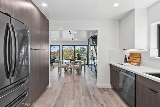 kitchen featuring light wood-type flooring, dark brown cabinets, and appliances with stainless steel finishes