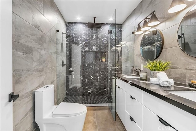 bathroom with toilet, tile walls, vanity, a shower with door, and tile patterned flooring